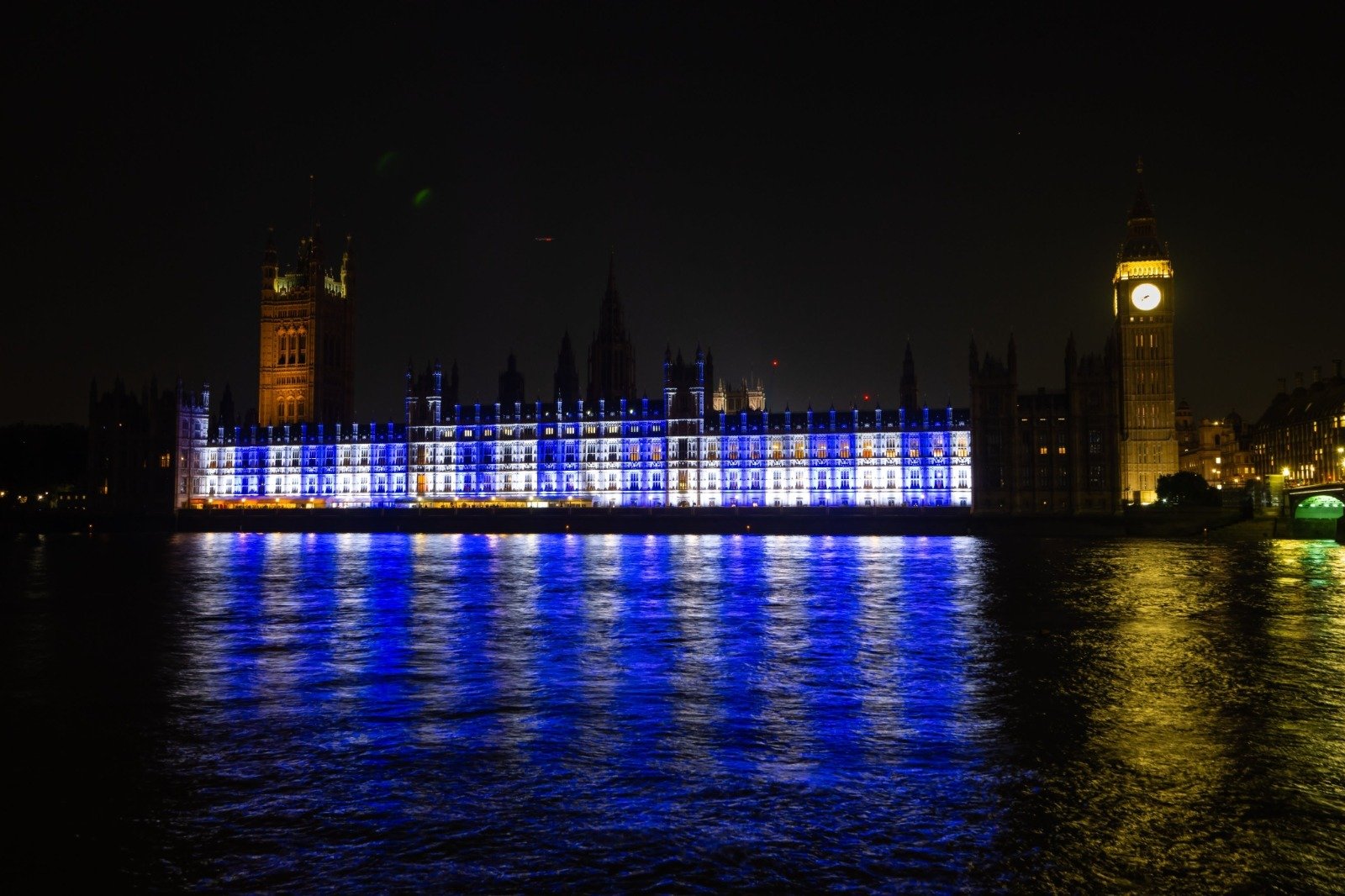 Image in @MarioNawfal's post: The British Parliament in Westminster is lit up in blue and white colors, as a sign of solidarity w…
